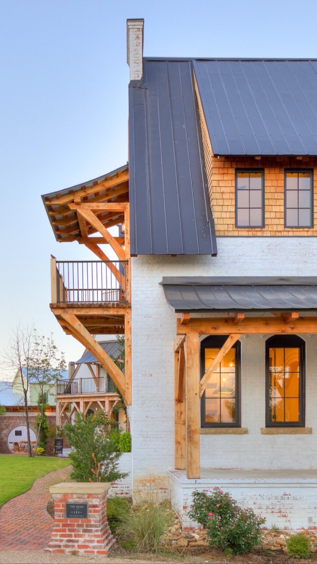 Exterior of a finished home at The Bend at Carlton Landing — exposed timber-frame brackets, painted brick, dark metal roof
