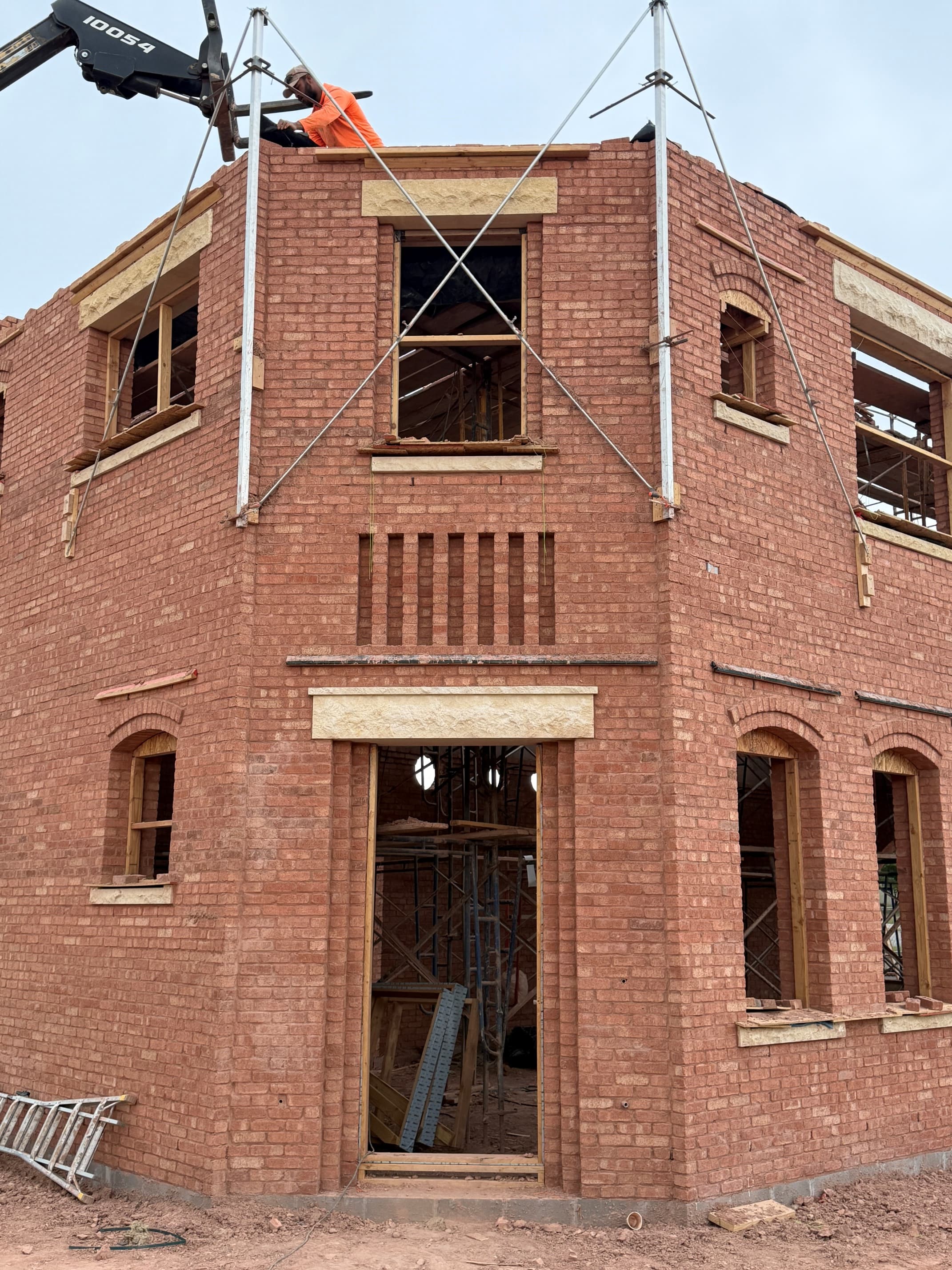 Apollo Workspace under construction in Edmond, brick masonry walls rising with a worker on top of the corner course