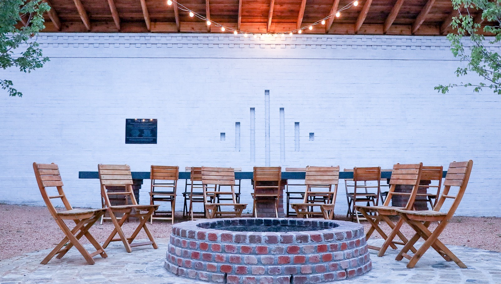 Central courtyard at The Bend at Carlton Landing — brick paths and gathering seating around a long communal table in late afternoon light.