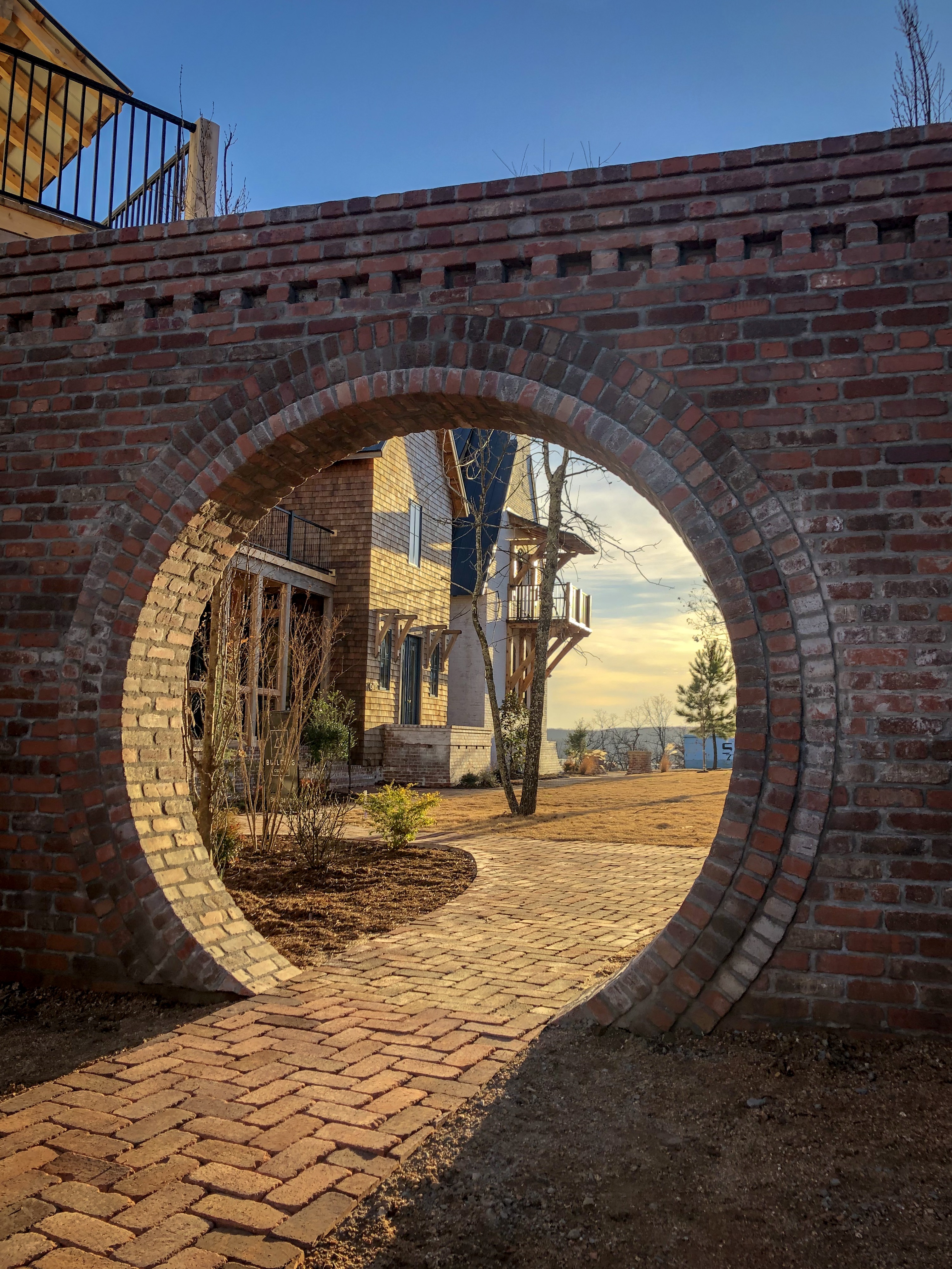 The brick moon-gate at The Bend at Carlton Landing, opening onto the central gathering courtyard in late afternoon sun